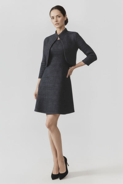 Woman wearing a dark gray dress with a matching jacket on a light gray background