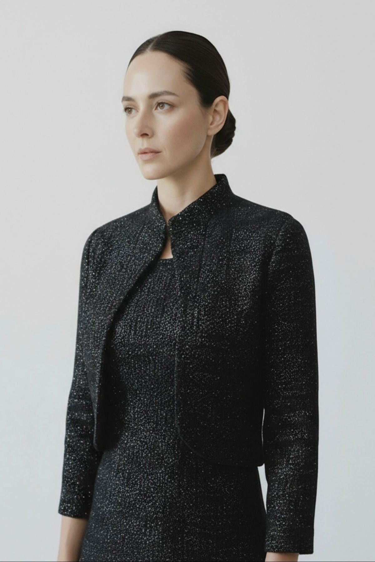 Woman wearing a black textured jacket against a light gray background