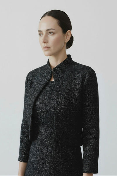 Woman wearing a black textured jacket against a light gray background