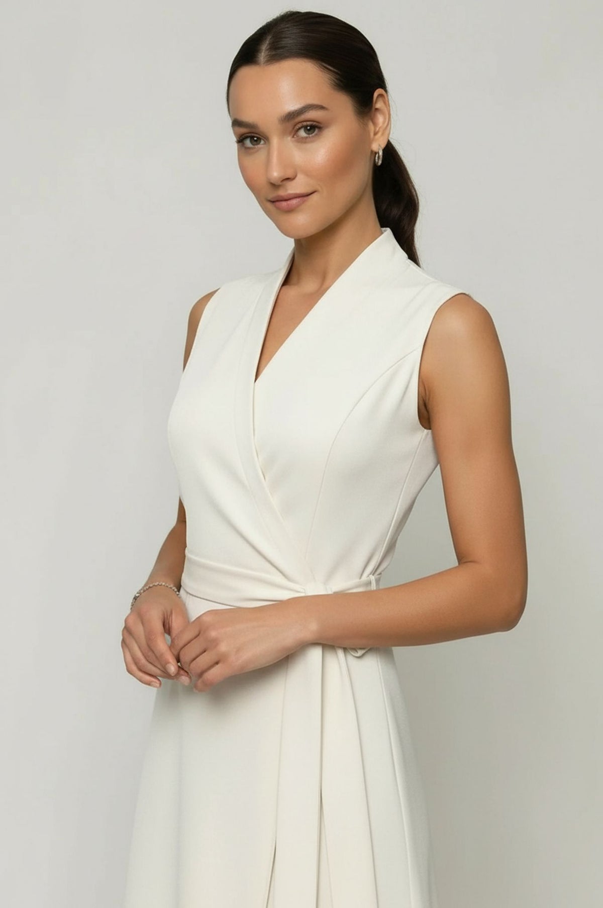 Woman wearing a white sleeveless dress against a plain background