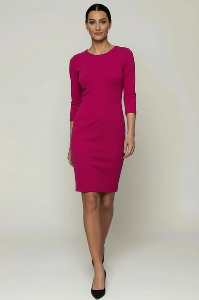 A woman with dark brown hair pulled back in a sleek center-parted style wears a fitted magenta pink dress. The dress features a round neckline, three-quarter-length sleeves, a defined waist with subtle diagonal seam detailing, and a knee-length fitted skirt. 