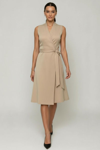 Woman wearing a beige sleeveless dress with a belt on a white background